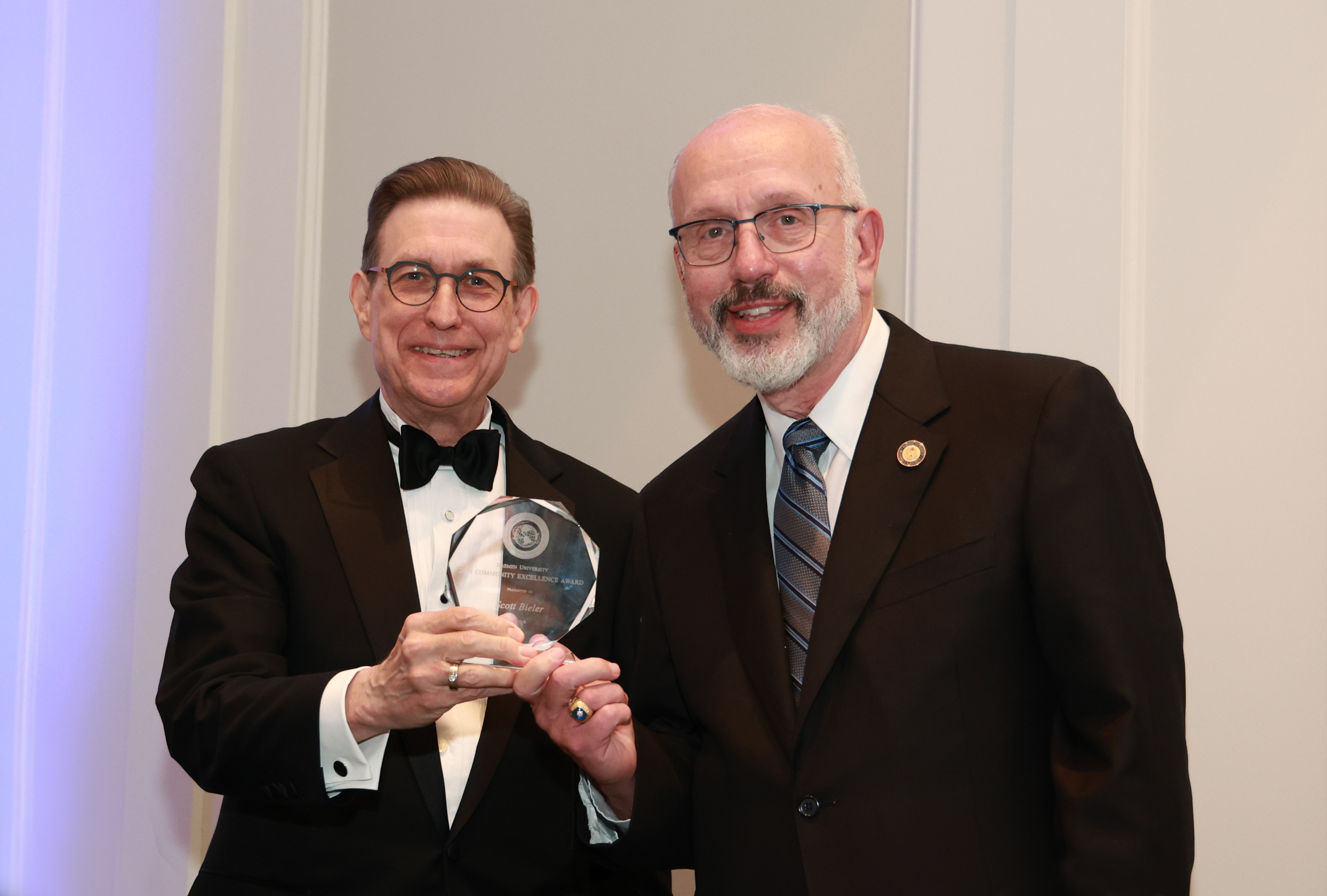 President Gary A. Olson in tuxedo and Scott Bieler in suit holding excellence award