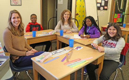 Teachers sitting at desk helping grade school children