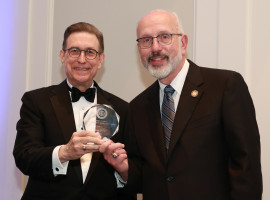 President Gary A. Olson in tuxedo and Scott Bieler in suit holding excellence award